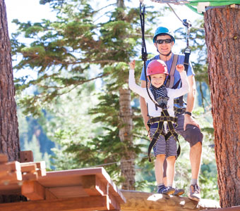 a father watching his child prepare to zipline in a kids adventure course